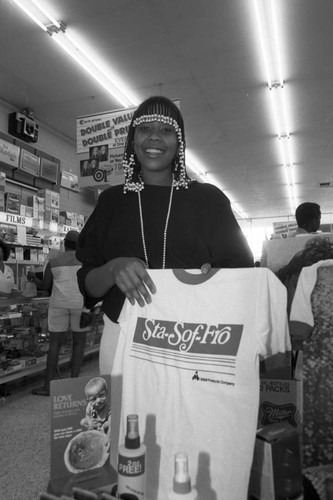 Woman holding Sta-Sof-Fro T-shirt during a M+M B.A.R.A.C. (Black American Response To The African Crisis) promotion, Los Angeles, 1985