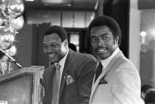 Larry Holmes and Jim Hill posing together at a press conference for the "Crown Affair" boxing event, Los Angeles, 1983