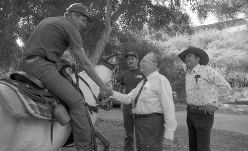 Inglewood Mayor Lee Weinstein talking with a mounted policeman in a park, Los Angeles, 1982