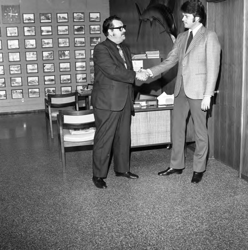 Two men shaking hands in a realtor's office, Los Angeles