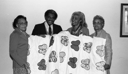 African American women and a man posing with a butterfly quilt, Los Angeles, 1986