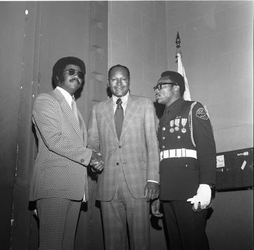 Tom Bradley posing with two unidentified men, one in uniform, Los Angeles, 1974