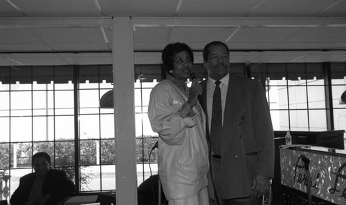 Frank Holoman talking through a microphone with Marla Gibbs at the opening of his restaurant, Frank's Place, Los Angeles, 1998