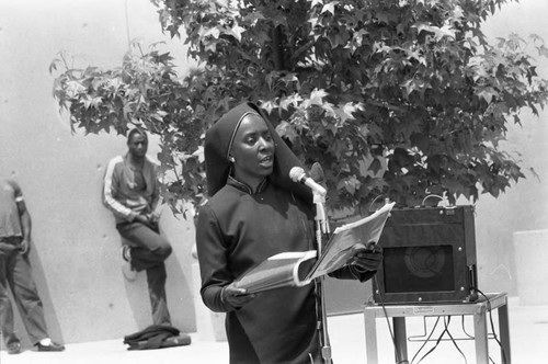 Black Muslim woman speaking at an outdoor microphone, Los Angeles, 1982