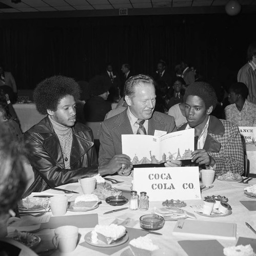 Black Business Association luncheon participants posing together at a table, Los Angeles, 1973