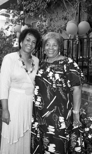 Toni Carter posing with a woman at a champagne buffet, Los Angeles, 1985