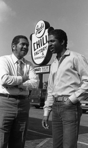 Lacey K. Oliver and Vincent Oliver standing in front of the family restaurant, Los Angeles, 1985