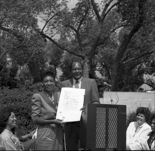 Maxine Waters holding a commendation next to Tom Bradley, Los Angeles, 1986
