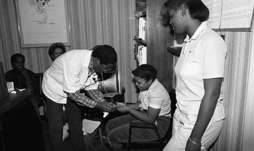 Dotson Medical Corporation staff examining a child during a health care screening event, Los Angeles, 1984