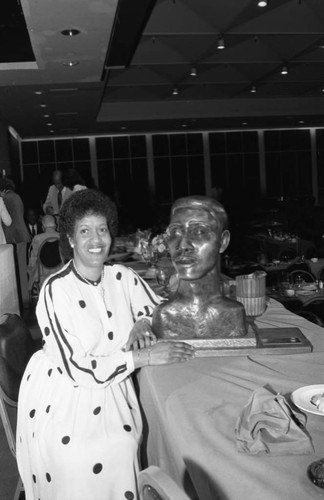 Myrlie Evers sitting next to a bust of Medgar Evers, Los Angeles, 1983