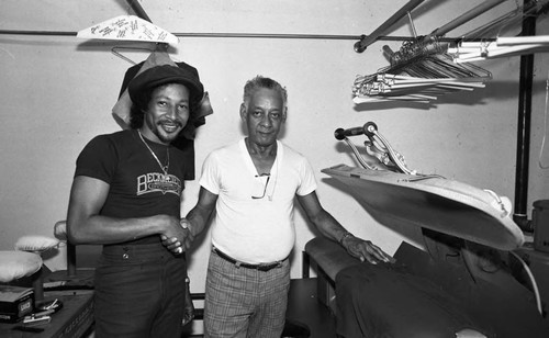 Augie Johnson posing with a staff member of Augie's Distinctive Cleaners, Los Angeles, 1983