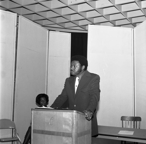 Unidentified man speaking from a lectern at Compton College, Compton, 1973