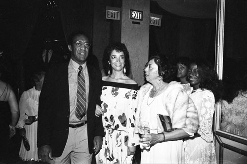 Bill Cosby and his wife Camille talking with Gertrude Gipson at a Neighbors of Watts benefit, Los Angeles, 1982