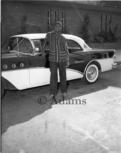 Young man next to motor vehicle, Los Angeles, 1956