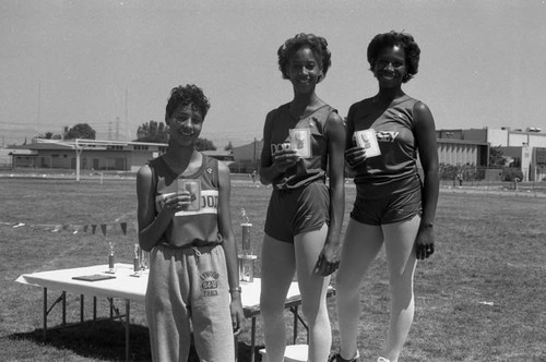 Lisa Nichols, Winnie Addison, and Patricia Fox holding track and field medals, Compton, 1984