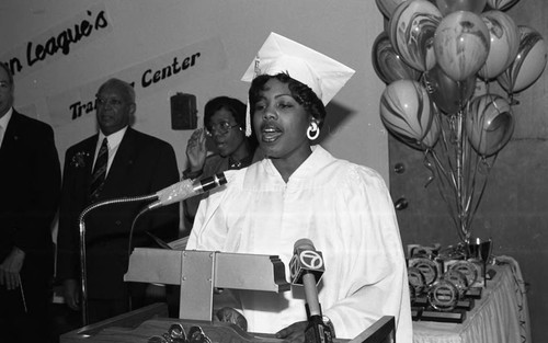 Urban League Training Center graduate standing at lectern during ceremonies, Los Angeles, 1993