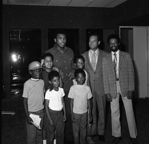 Muhammad posing with Douglas Dollarhide and children at a fitness center, Compton, 1973