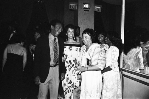 Bill Cosby and his wife Camille talking with Gertrude Gipson at a Neighbors of Watts benefit, Los Angeles, 1982