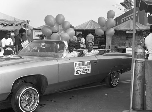 Black Agenda Business Fair participants posing in a convertible, Los Angeles, 1983