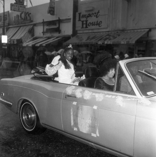 Cynthia Stewart waving from a convertible during the Compton Christmas Parade, Compton, 1973