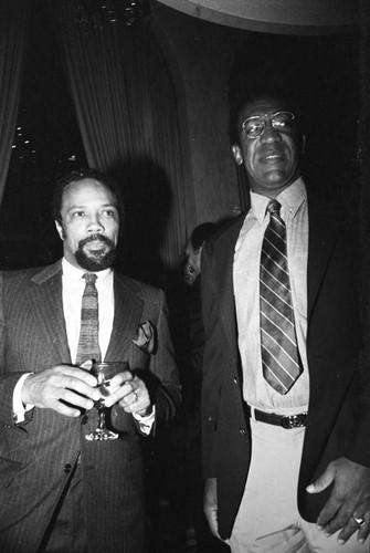 Bill Cosby standing with Quincy Jones at a Neighbors of Watts benefit, 1982