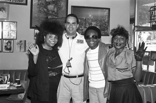 KGFJ staff member posing with others, Los Angeles, 1975