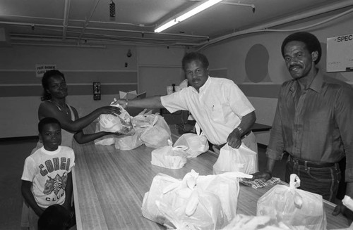 Black Track, Inc. food give-a-way participants receiving bags of food, Los Angeles, 1990