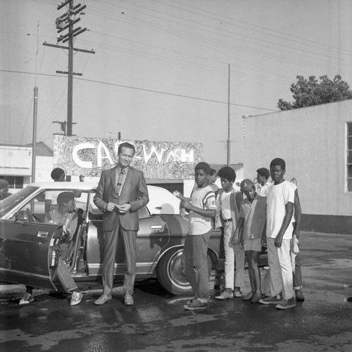 Douglas Dollarhide posing with young men during a car wash, Compton, 1971