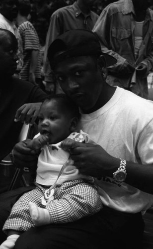 Joe Torry holding an infant at the Great Western forum, Inglewood, 1994