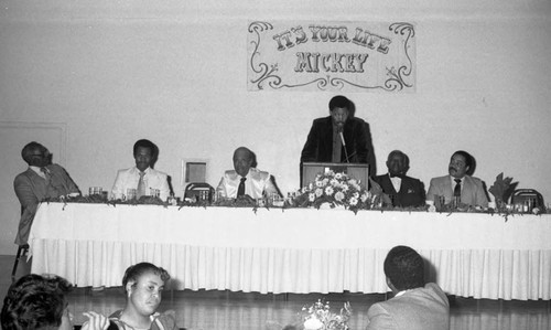 Man speaking at a tribute to Mickey Cureton, Los Angeles, ca. 1985