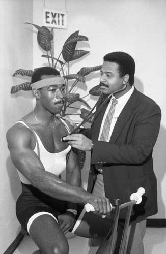 Baldwin Hills Medical staff member listening to a man's heart rate , Los Angeles, 1986