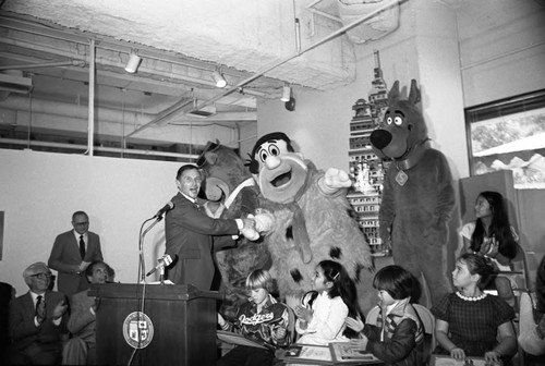 Children's Museum event guest Daryl Gates posing with Hanna-Barbera characters, Los Angeles, 1982