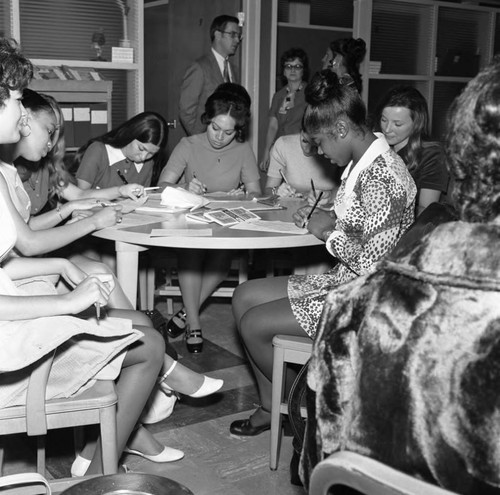 Young women sit together writing during Career Day at Compton College, Compton, 1971