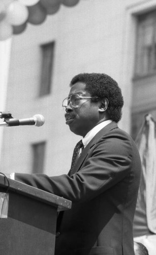 Unidentified man speaking at an outdoor lectern, Los Angeles, 1985