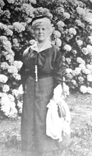 Portrait of Annie Bidwell standing in front of hydrangeas