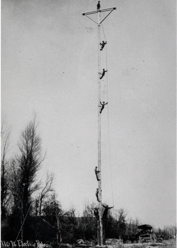 Men climb pole