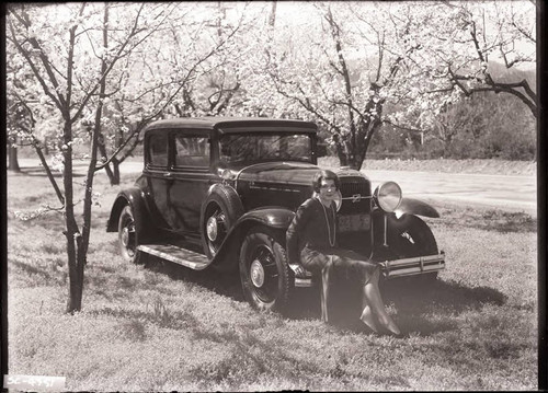 Woman sitting on bumper of a 1930's Buick