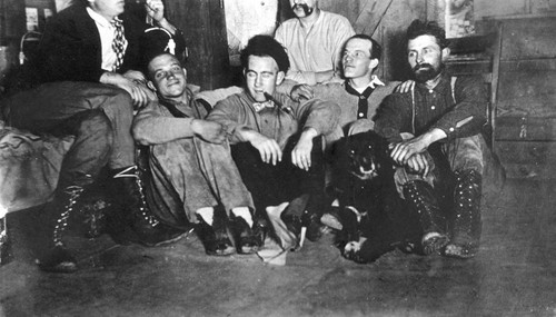 Railroad construction workers seated in tent with dog