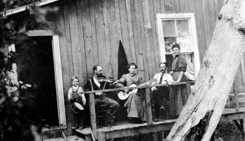 Group of people with musical instruments on porch of house at Finley Lake