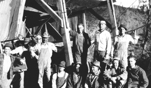 Logging crew standing in front of a corrugated shed