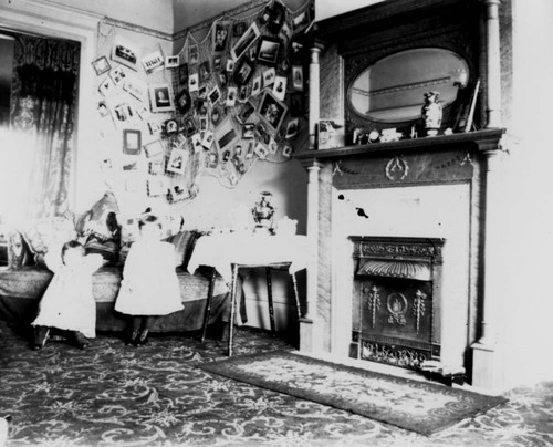 Two young children inside a home, next to fireplace