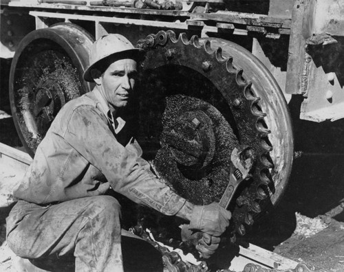 Workman adjusting sprocket wheel during construction of Shasta Dam
