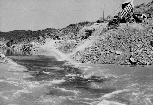 Placing material for cofferdam at Shasta Dam construction site