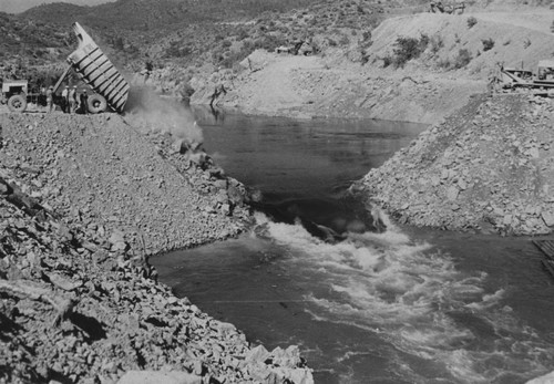 Placing material for cofferdam at Shasta Dam construction site