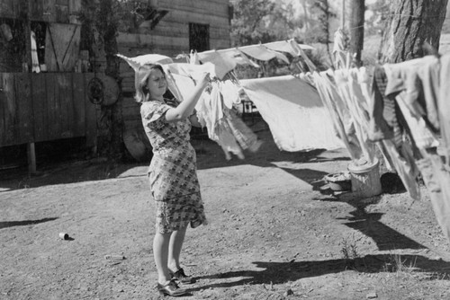 Woman hanging clothes in squatter's camp, Shasta Dam construction