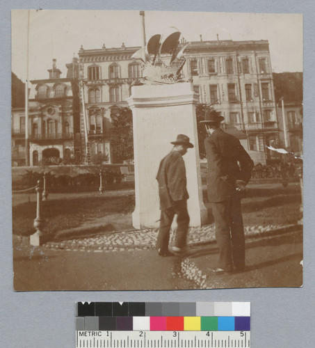 [small photo, back view of 2 men (1 Chinese) in front of Robert Louis Stevenson monument in Portsmouth Square]