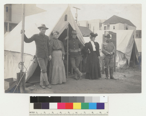 [Soldiers and women posing before tent.]