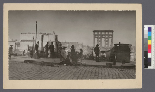 [Refugees sitting and cooking in street against a background of ruins. Fairmont Hotel on Nob Hill in distance, center.]