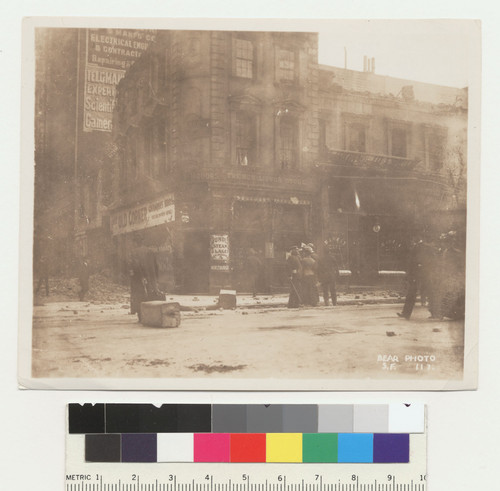 [Street scene at French Liquor Store, unidentified location. Man in street dragging case of belongings. No. 117.]