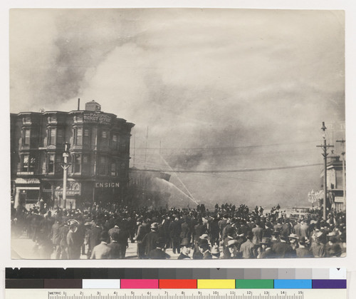 [Crowd gathered in street watching fire. At foot of Market St. near Ferry Building.]